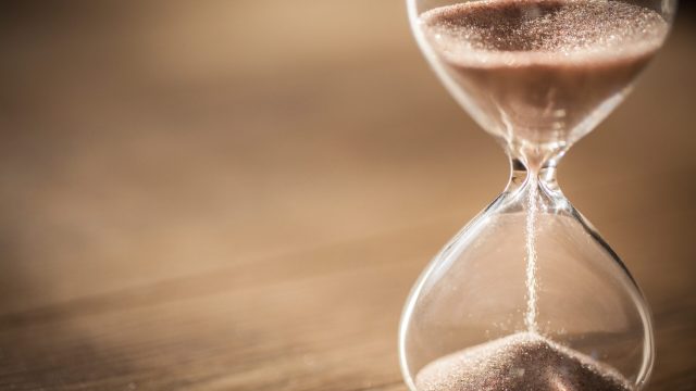 Sand running through the bulbs of an hourglass measuring the pas